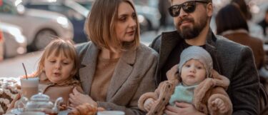 Family of four relaxing at lunchtime during their Europe holiday trip outdoors