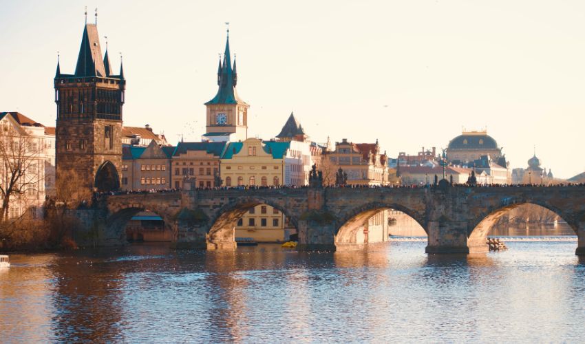Panoramic view of Charles Bridge and the Vltava River in Prague during a hazy sunset