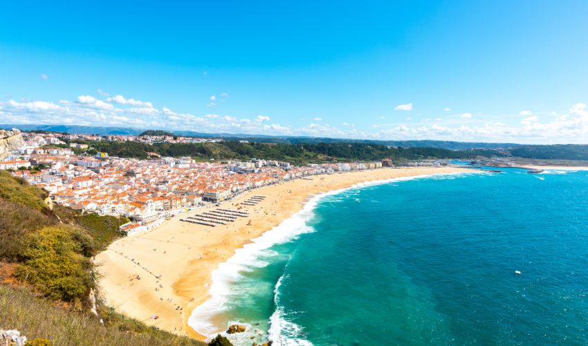 view of a vast sandy beach and turquoise ocean next to a coastal town in Alentejo, Portugal